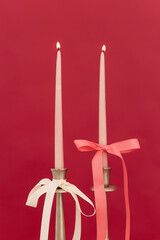 Elegant candlelight ceremony with pink and cream ribbons against a vibrant red backdrop