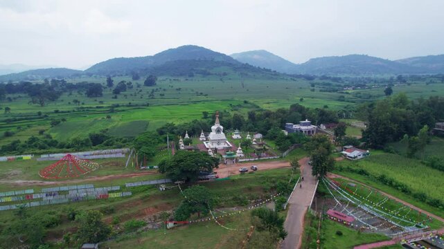 Aerial view of Jiranga Buddhist Monastery, set in a green valley surrounded by hills, boasts a golden-roofed structure with courtyards and pathways, radiating tranquility.
