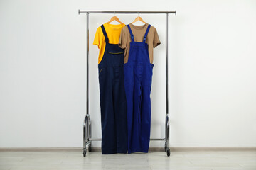 Workers' uniforms on clothing rack near grey wall indoors