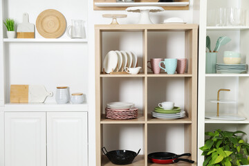 Shelving units with kitchenware near white wall indoors