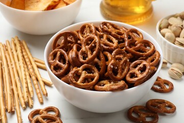 Delicious pretzel crackers and other snacks on white table, closeup