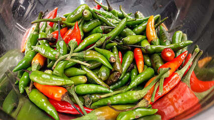 A Bunch of Small Green, Red, Orange Shiny Cayenne Peppers in a Stainless Steel Bowl Close Up. Raw Materials for Sambal Spices and Asian Spices, Especially Indonesia and India. Fresh Condition Fruits