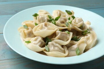 Delicious pelmeni with green onion on blue wooden table, closeup