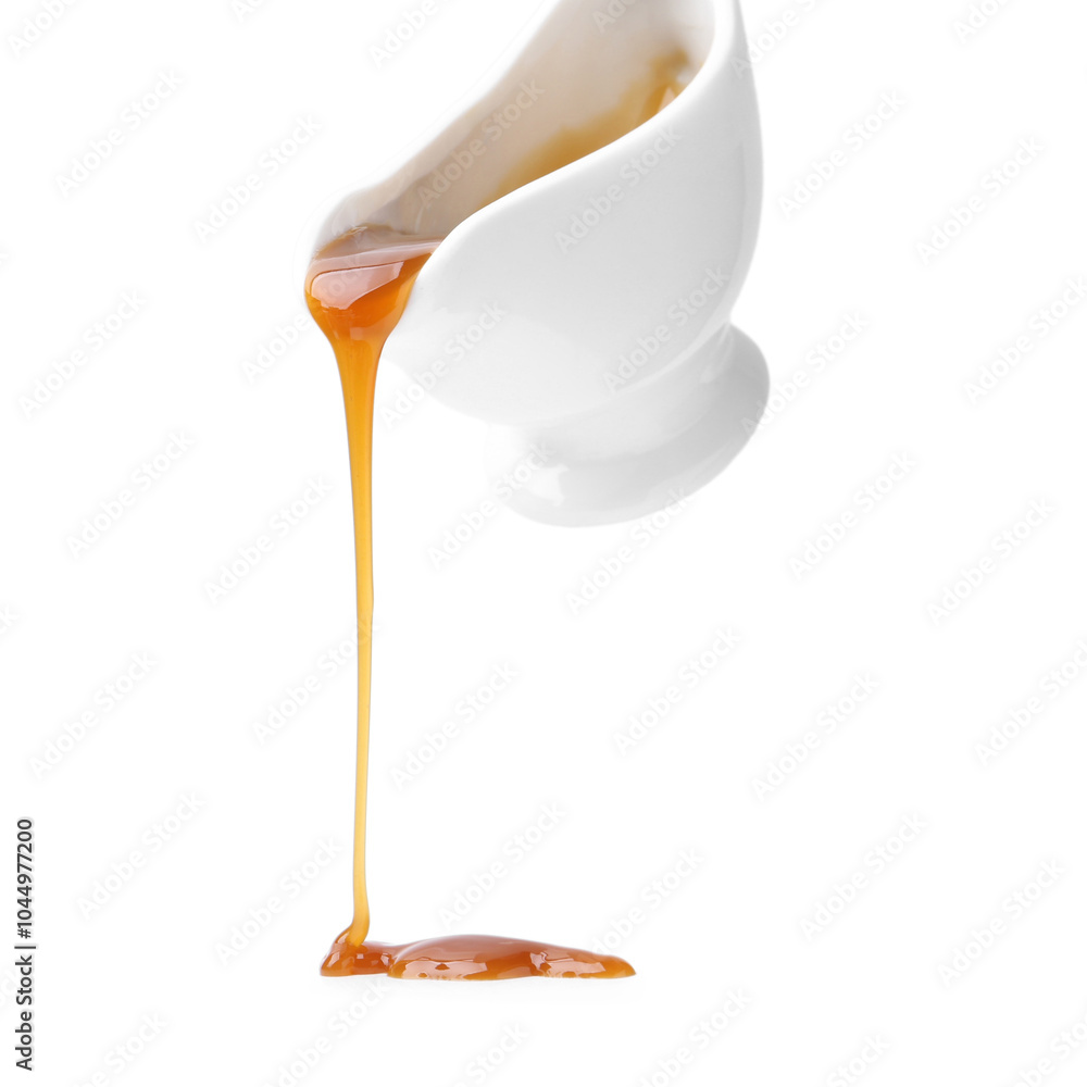 Poster Tasty caramel sauce dripping from gravy boat on white background, closeup