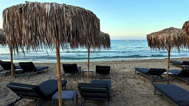 Sun loungers and parasols on the beach for sunbathing on Mediterranean Sea in Crete, Greece