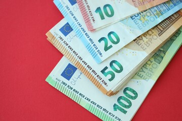 Big amount of one hundred, twenty, ten and fifty euro money bills on red background