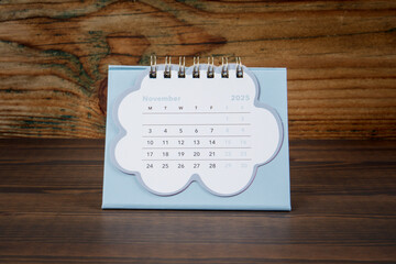 November 2025. cardboard desk calendar on a wooden texture background