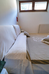 Morning in a bright and sunny modern white bedroom interior with wooden furniture