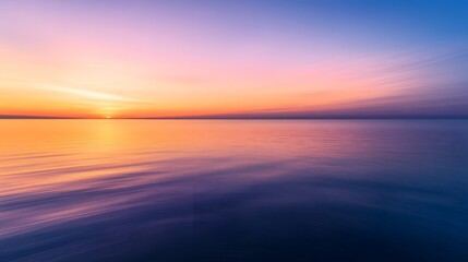 Fototapeta premium A calm sea at sunset, with the horizon blending into a gradient of purples and oranges, creates an atmosphere that feels serene and peaceful.