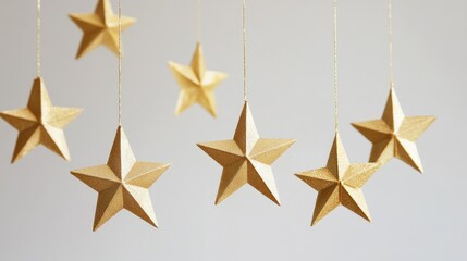 Obraz premium Graceful gold stars hanging from strings, arranged symmetrically against a simple white background, for a subtle festive look.