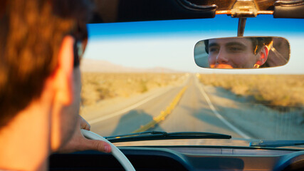Male Driver Reflected In Mirror Driving Classic Open Top Car On Road Trip Through Countryside
