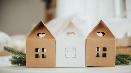 Decorative houses made of cardboard displayed indoors with a cozy background