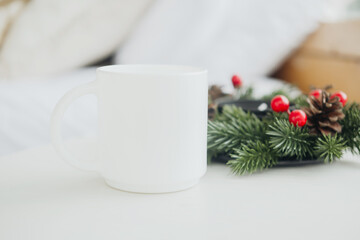 Cozy winter morning with a blank mug and festive pine decor on a table