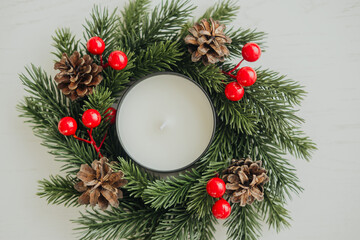 Christmas candle centerpiece with pinecones and holly on a table