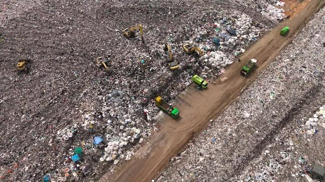Aerial top view of A Huge Waste, garbage, dump, rubbish landfill. A landfill compactor, group of workers sort out the garbage in the landfill. Trash trucks dump waste polluting products.