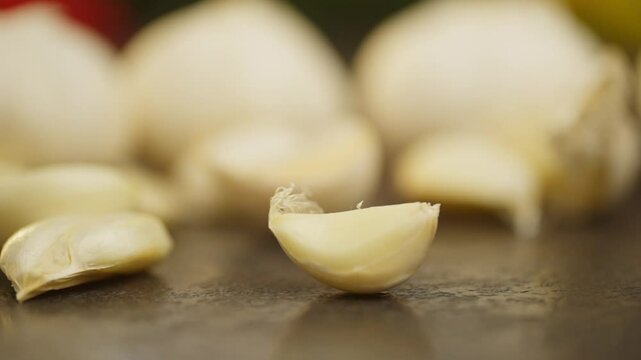 Slow motion background video of a clove of garlic spinning on a table against a background of vegetables. Fresh organic vegetables for cooking delicious meals in the kitchen. High quality FullHD 