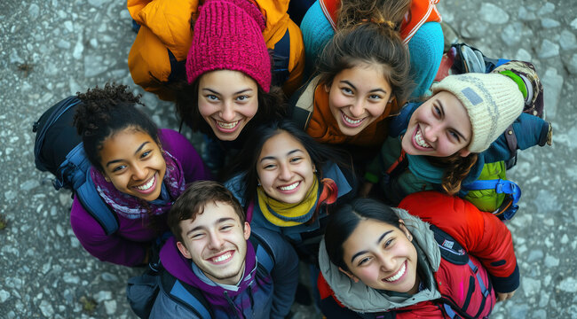 Un groupe de jeunes gens souriants, repr&eacute;sentant diverses ethnies et groupes d'&acirc;ge, regardant vers l'objectif, vue de dessus.