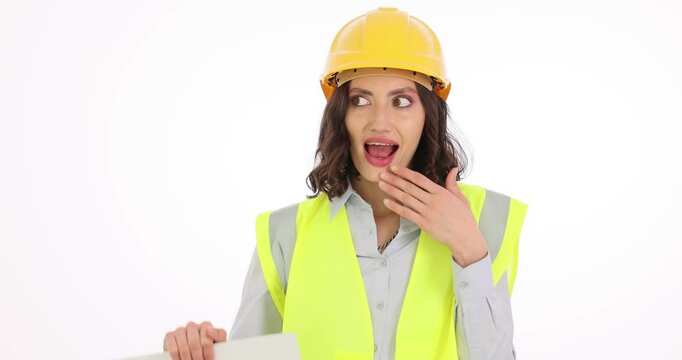 Woman builder raises paper with word OOPS covering mouth and rolling eyes. Young female engineer makes sarcastic expressions regarding work accidents