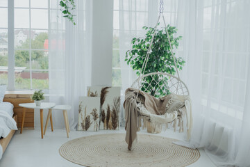 Cozy indoor corner with a hanging chair and greenery in natural light