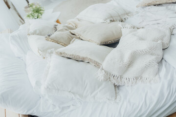 Fototapeta premium Cozy bed with textured pillows and blankets in a bright, airy room