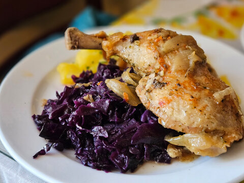 Hungarian braised chicken leg with slow-cooked red cabbage serving on the white plate.
