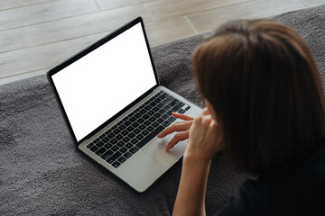 A person working on a laptop at home during the daytime on a cozy couch