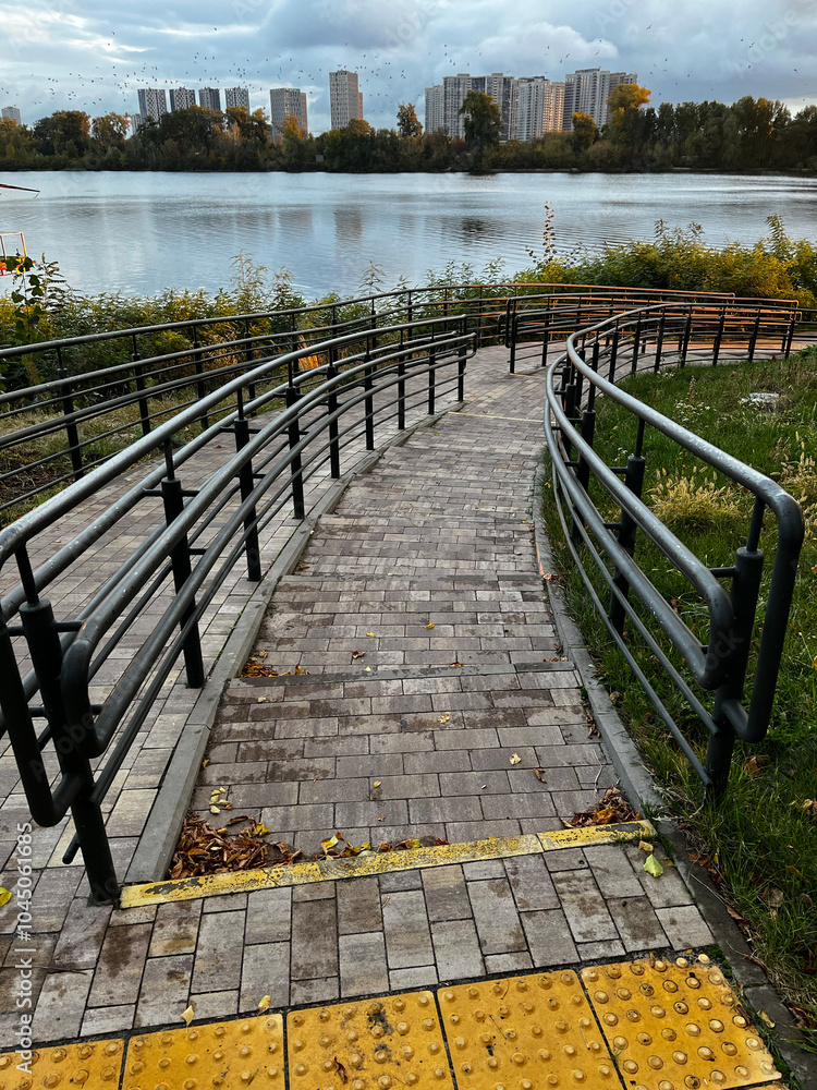 Poster a walkway with a yellow line on it leading to a bridge over a body of water. the walkway is lined wi