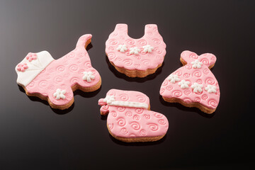 Baby cookies decorated with glaze on a black background. Baby girl.