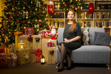 A beautiful woman is waiting for guests in the living room near the Christmas tree for a festive...