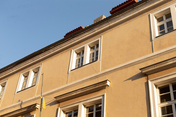 Fototapeta premium Imagine a tall and impressive building with an abundance of windows that light up the interior, proudly displaying a flag on its side