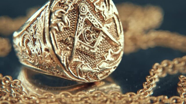 A macro detailed shot of a golden textured freemasons ring, on a mirror reflection stand, illuminati symbol, studio light, 4K video, TILT DOWN, movement, necklace shallow depth of field, Alchemy