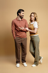 A middle aged couple smiles and chats closely while dressed casually.