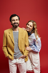 A cheerful couple dressed in fashionable attire enjoys each others company with smiles.