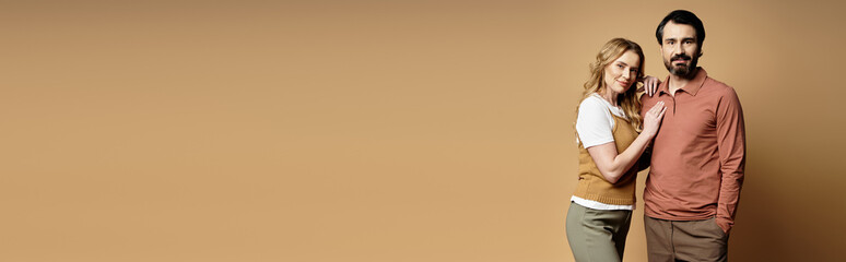 A relaxed middle aged couple stands close together, showcasing their unique style and connection.