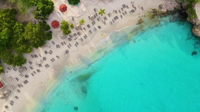 Top-down drone view of turquoise beach waters at Playa Abou in Curacao, highlighting the natural beauty of the tropical shoreline, orbit and descend at sunrise