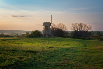 View of an ancient wooden windmill on the banks of the Sorot River on a foggy summer morning,...