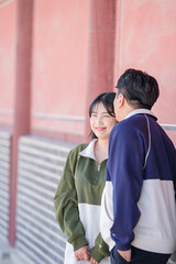 A sporty Korean couple, a man in his 30s and a woman in her 20s, wearing tracksuits, spends their time together happily at a historical building in Seoul, South Korea.