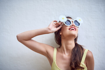 Wall, woman and flowers in sunglasses for fashion, trendy style and smile with pose for pride....
