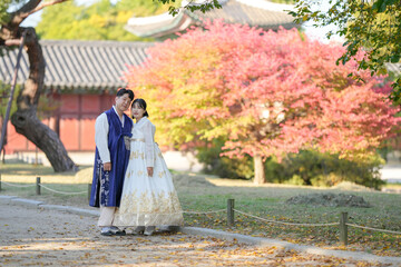 A Korean couple in their 30s and a woman in their 20s are happily wearing Hanbok and spending time...