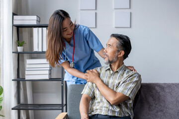 Smiling nurse comforting elderly patient at home