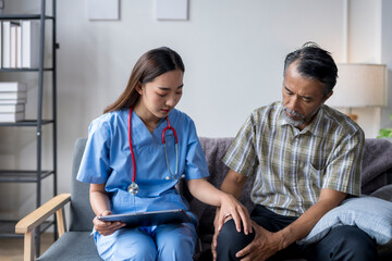 Fototapeta premium Female doctor comforting senior patient experiencing knee pain at home