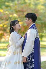 A Korean couple, a man in his 30s and a woman in her 20s, are spending time together in a historic park in Seoul, South Korea.