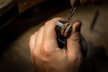 Jeweler puts diamond to golden wedding luxury ring. Selective focus. Macro photo.
