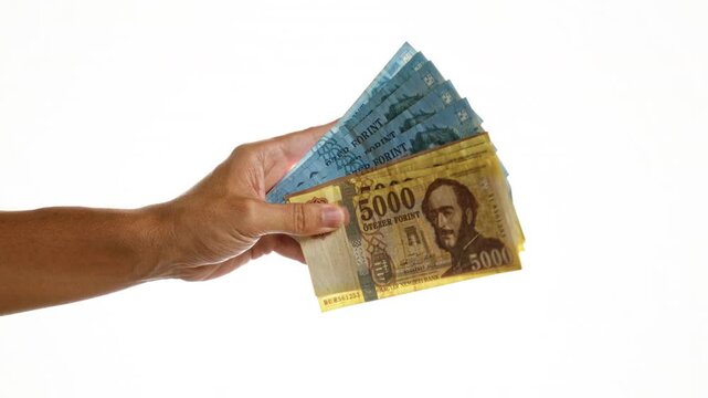 Hand holding hungarian forint banknotes isolated over a white background wall focusing on money from hungary with a close-up view showing the currency in various denominations