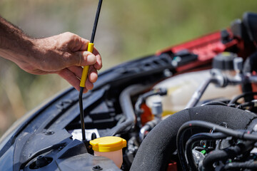 Young overwhelmed man seeing broken car engine. On your vacation to the beach, your rental vehicle broke down.