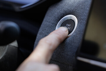 Close-up of a man's hand starting the car engine with the Start Stop button.