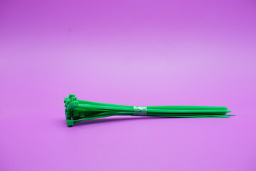 Fototapeta premium bundle of green zip ties isolated on purple background. Cable ties or cable ties, straps that can be used for various purposes.