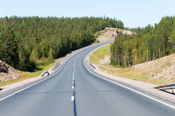 Obraz premium Empty asphalt highway through the hills and forests in Karelia, sunny summer day