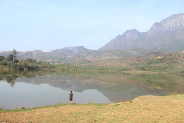 pessoa nas margens da represa do mosquito com serra do cara&ccedil;a ao fundo em catas altas, minas gerais 