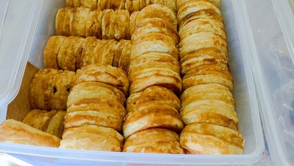 Close-up of a container filled with stacks of round, golden brown, sweet Japanese pancakes, a popular street food snack.